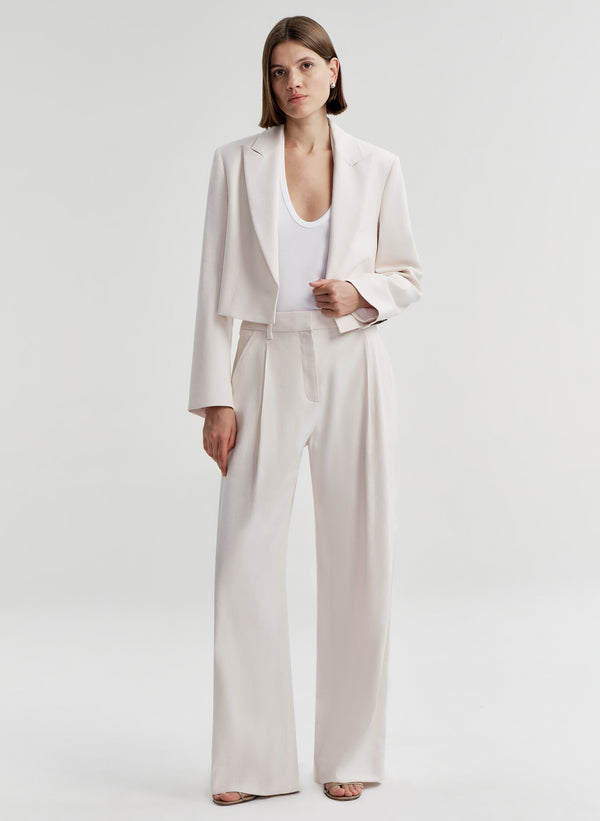 Woman wearing cream colored linen pants with a matching jacket 