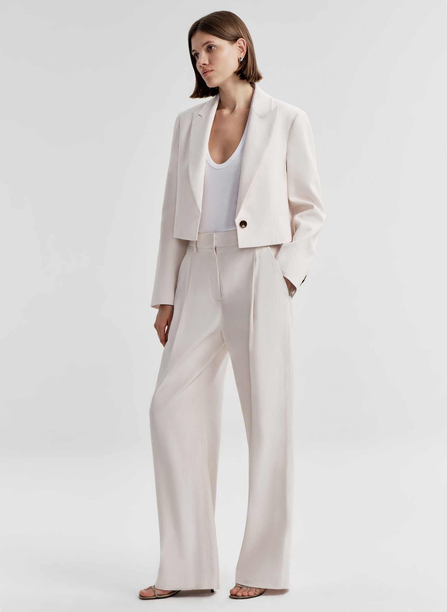 Woman wearing cream colored linen pants with a matching jacket 