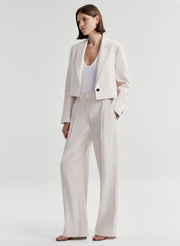 Woman wearing cream colored linen pants with a matching jacket 
