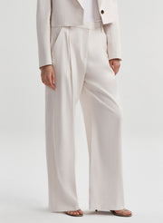 Woman wearing cream colored linen pants with a matching jacket 