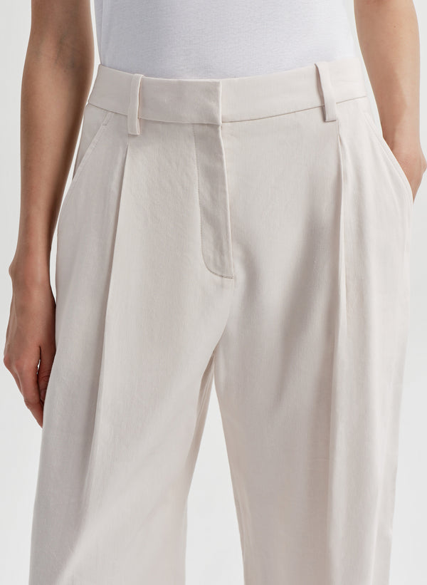 Beige linen pants worn by a woman on a white background