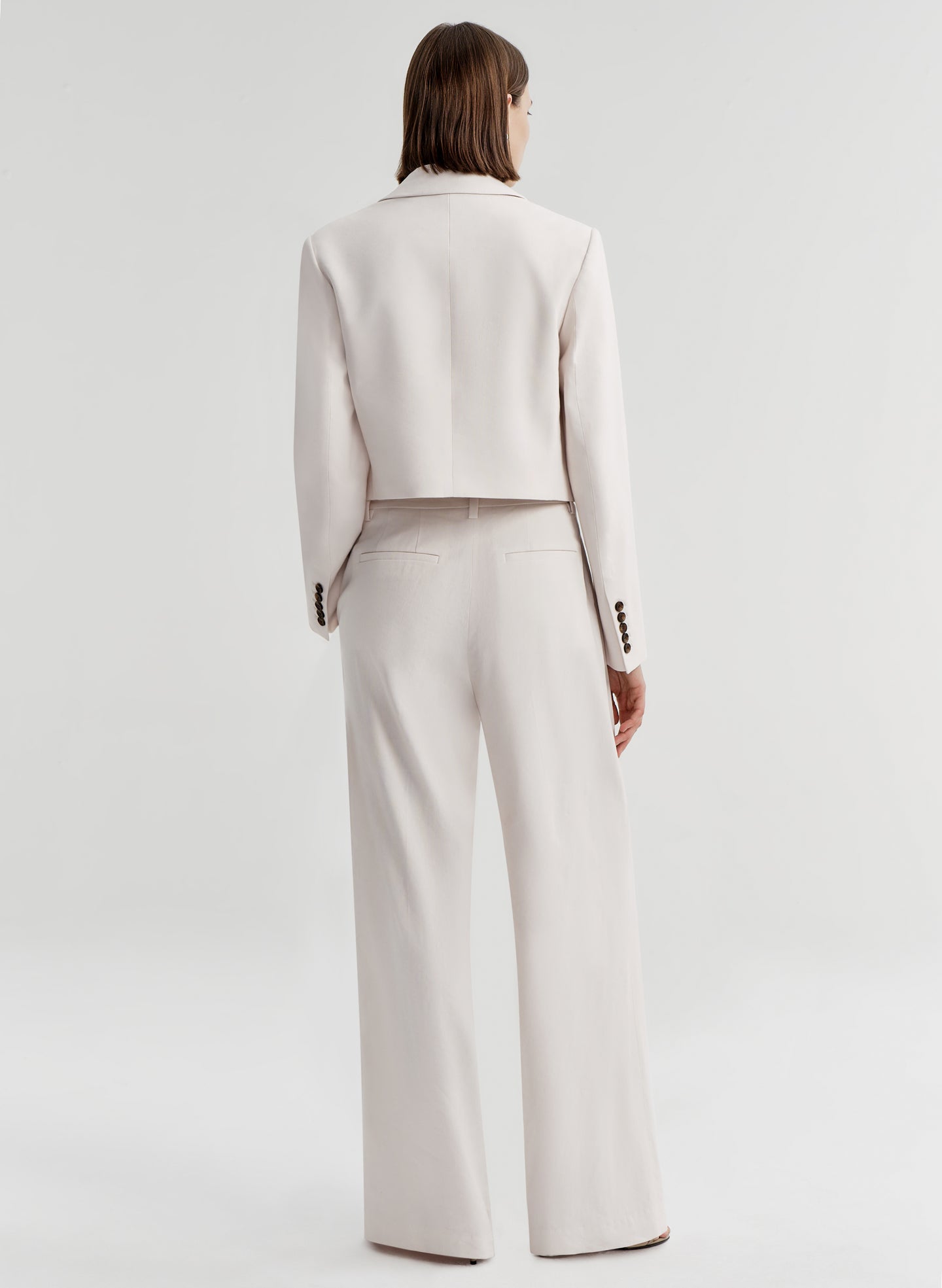 Woman wearing cream colored linen pants with a matching jacket 