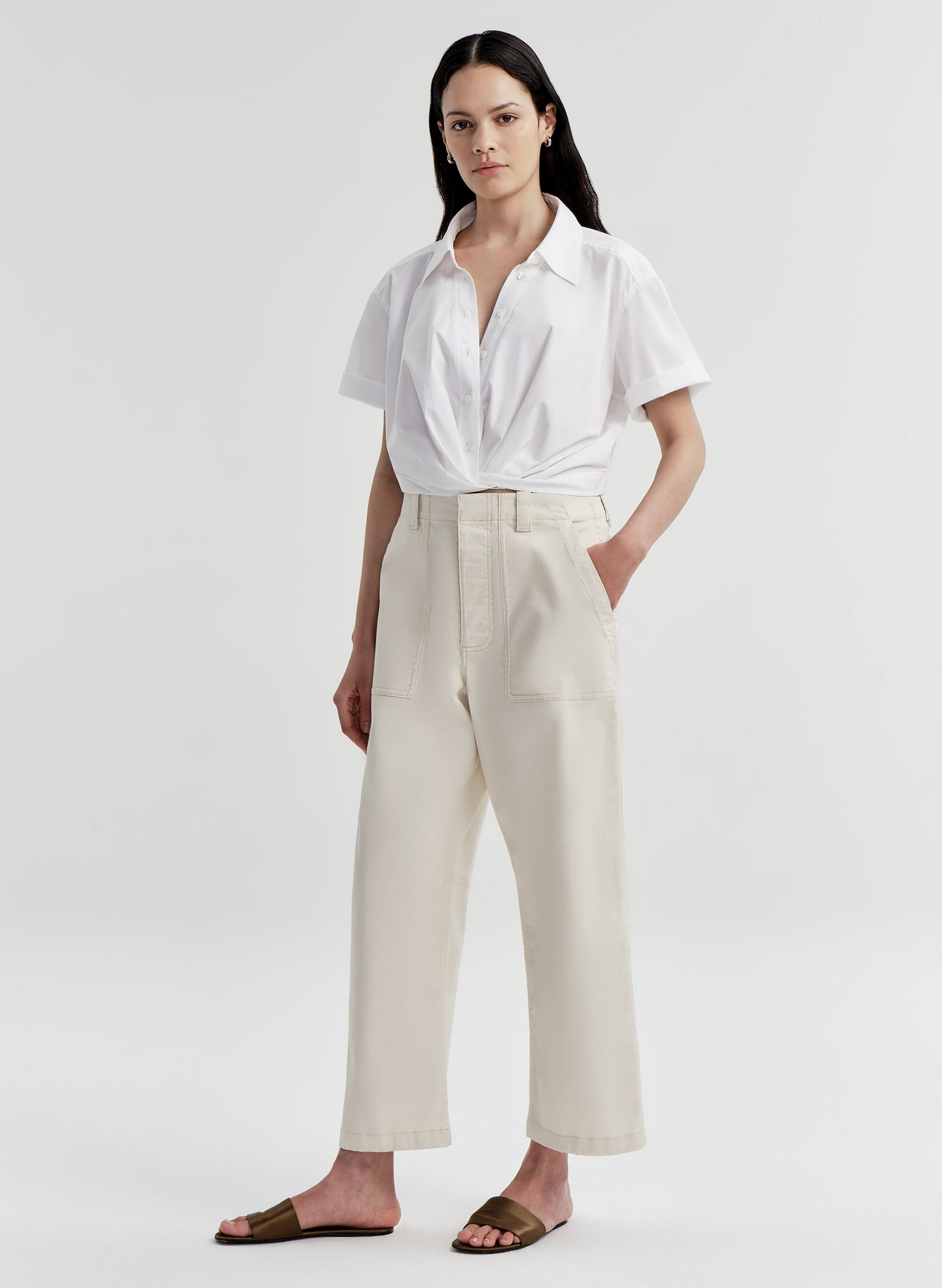 Woman wearing a white shirt and beige twill pants on a white background