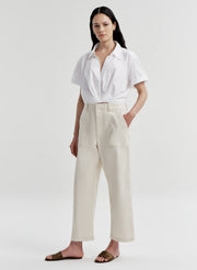Woman wearing a white shirt and beige twill pants on a white background