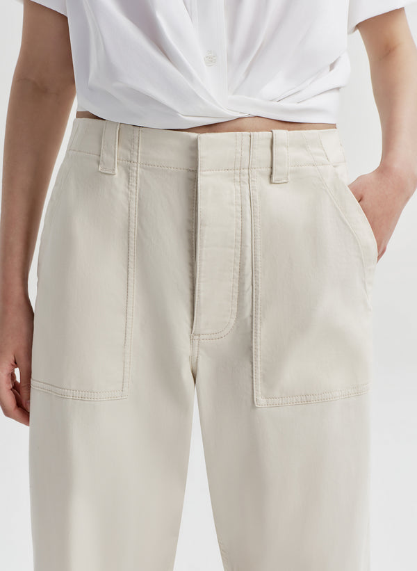 Close-up of woman wearing beige twill pants and a white top on a light gray background