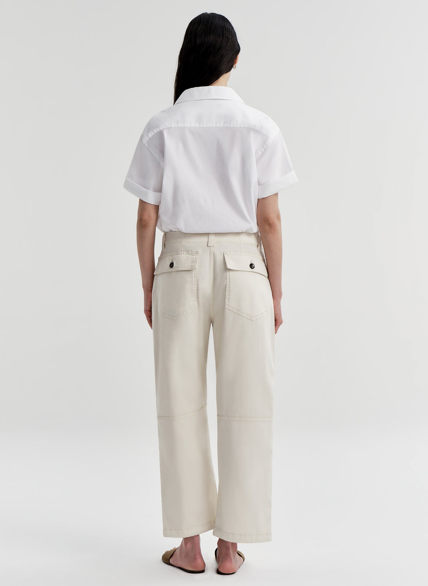 Woman wearing a white shirt and beige twill pants on a white background