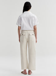 Woman wearing a white shirt and beige twill pants on a white background