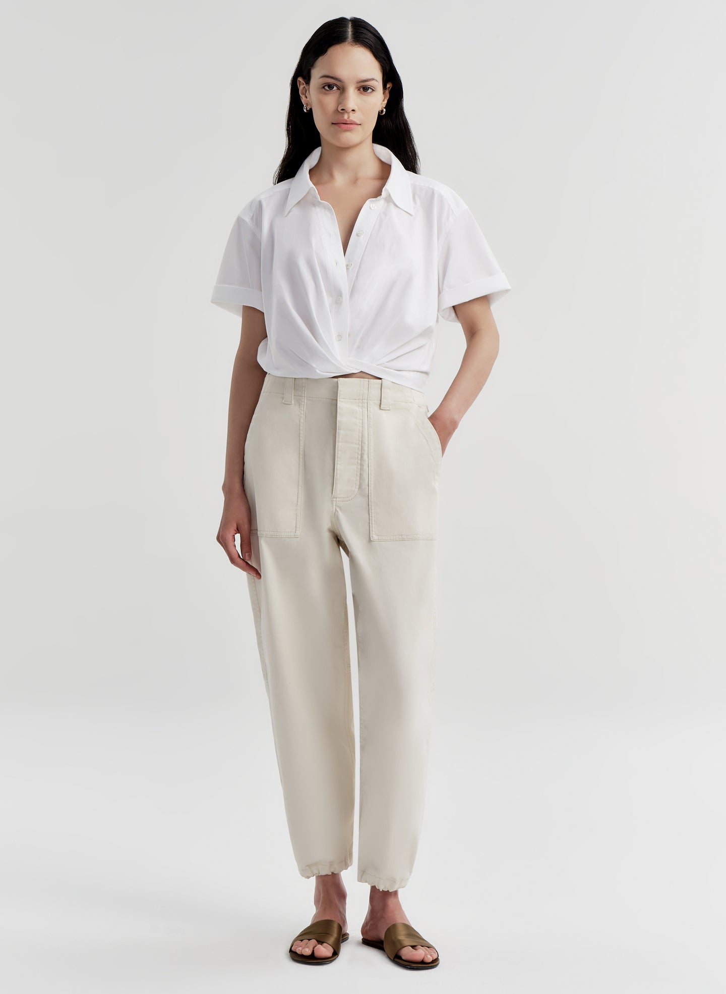 Woman wearing a white shirt and beige twill pants on a white background