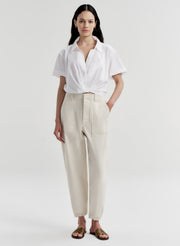 Woman wearing a white shirt and beige twill pants on a white background