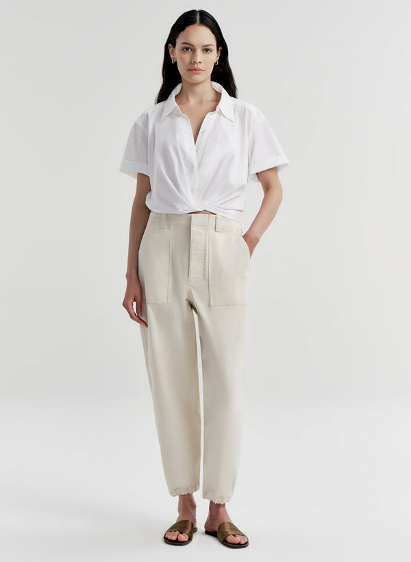Woman wearing a white shirt and beige twill pants on a white background