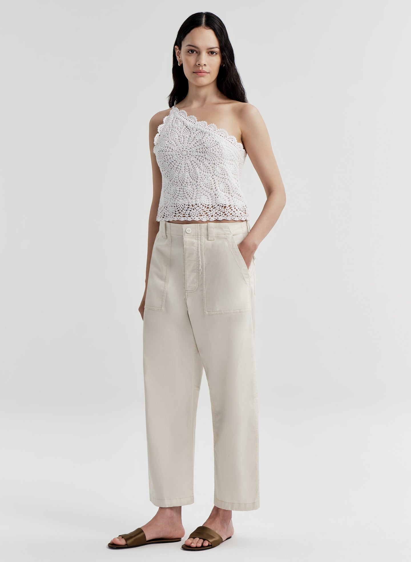 Woman wearing a white lace top and beige pants on a white background