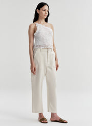 Woman wearing a white sleeveless top and beige pants on a light gray background