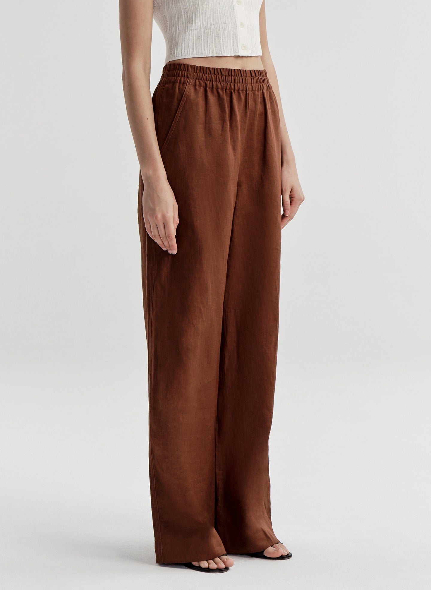 Woman wearing brown linen pants on a white background