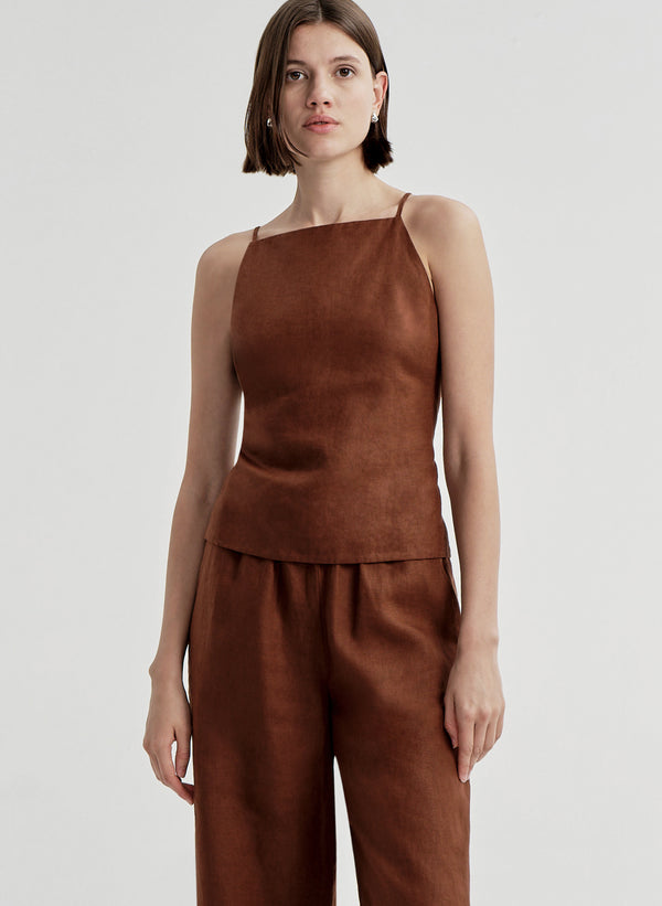 Woman wearing a brown sleeveless top and matching  pants on a light gray background