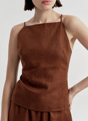 Woman wearing a brown sleeveless top and matching  pants on a light gray background