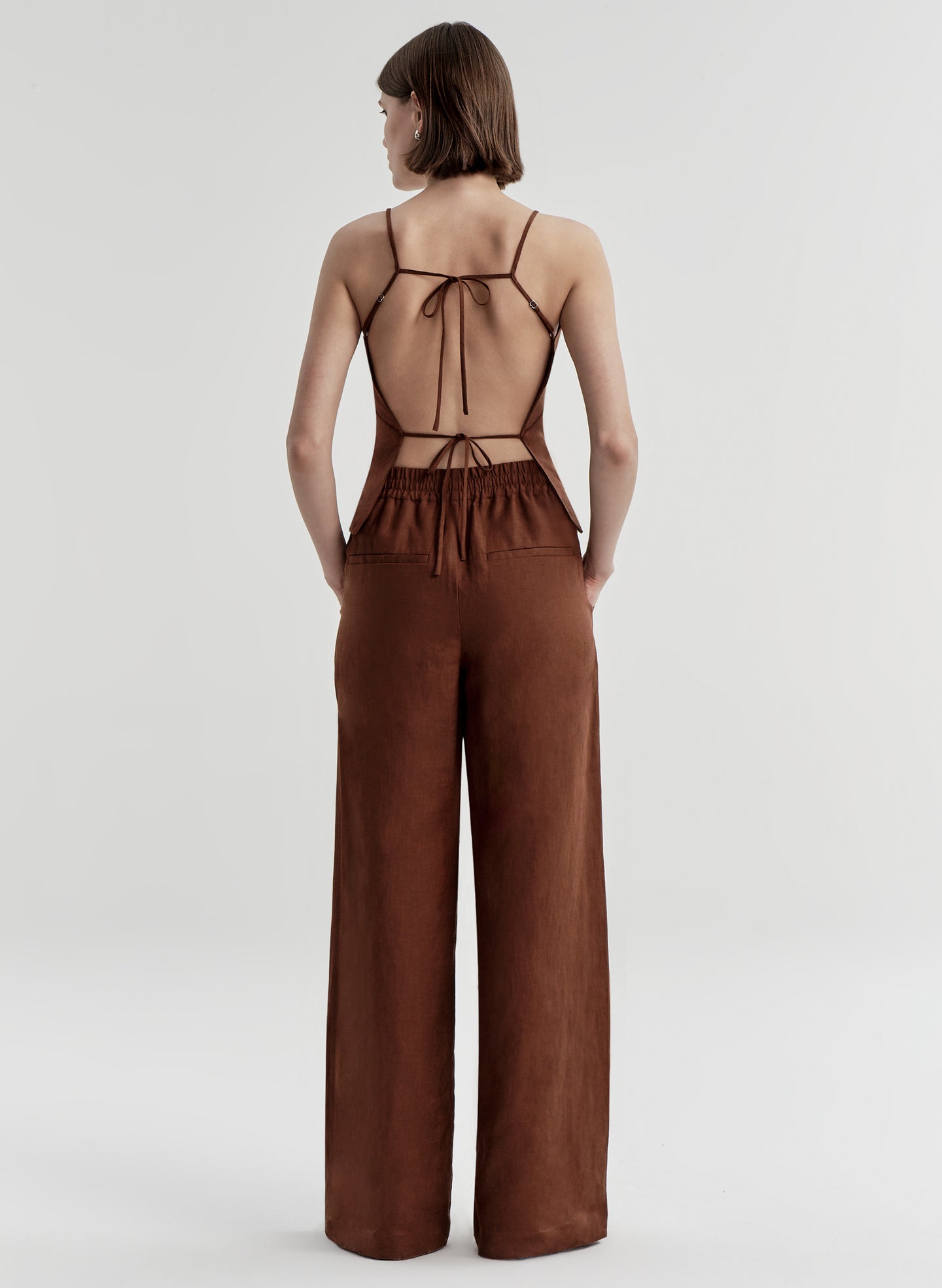 Woman wearing a brown top with open back on a white background
