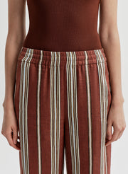 Woman wearing brown and beige linen striped pants on a white background