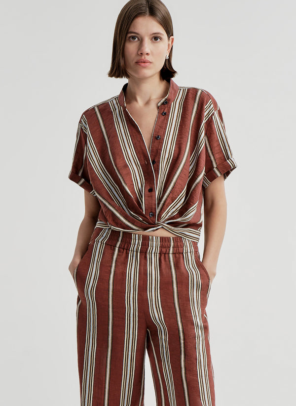 Woman wearing a brown and white striped linen top and matching pants on a plain background