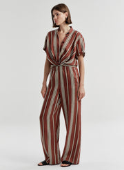 Woman wearing a brown and white striped linen top and matching pants on a plain background