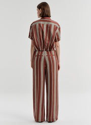Woman wearing a brown and white striped linen top and matching pants on a plain background