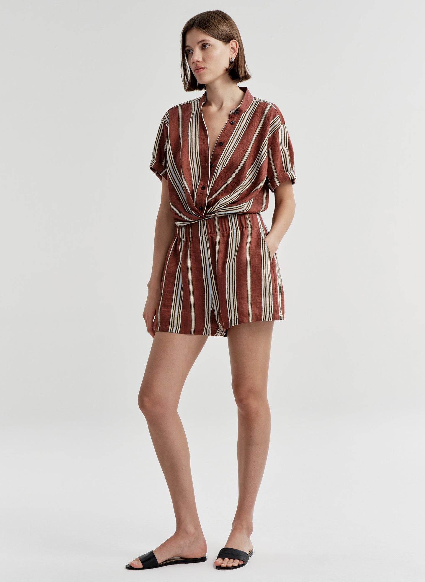 Woman wearing striped linen shorts with a matching top on a white background