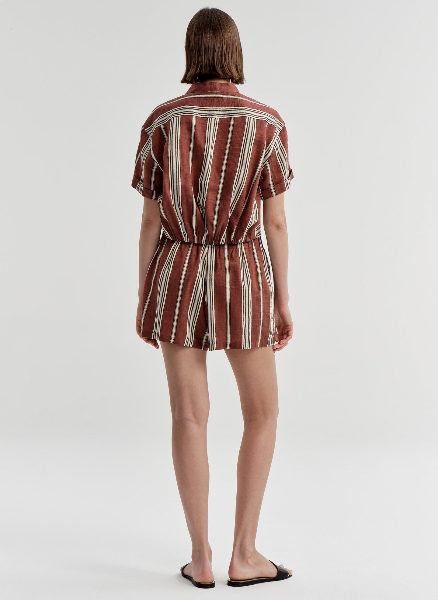 Woman wearing striped linen shorts with a matching top on a white background