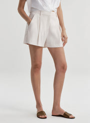 Woman wearing beige linen shorts on a plain background