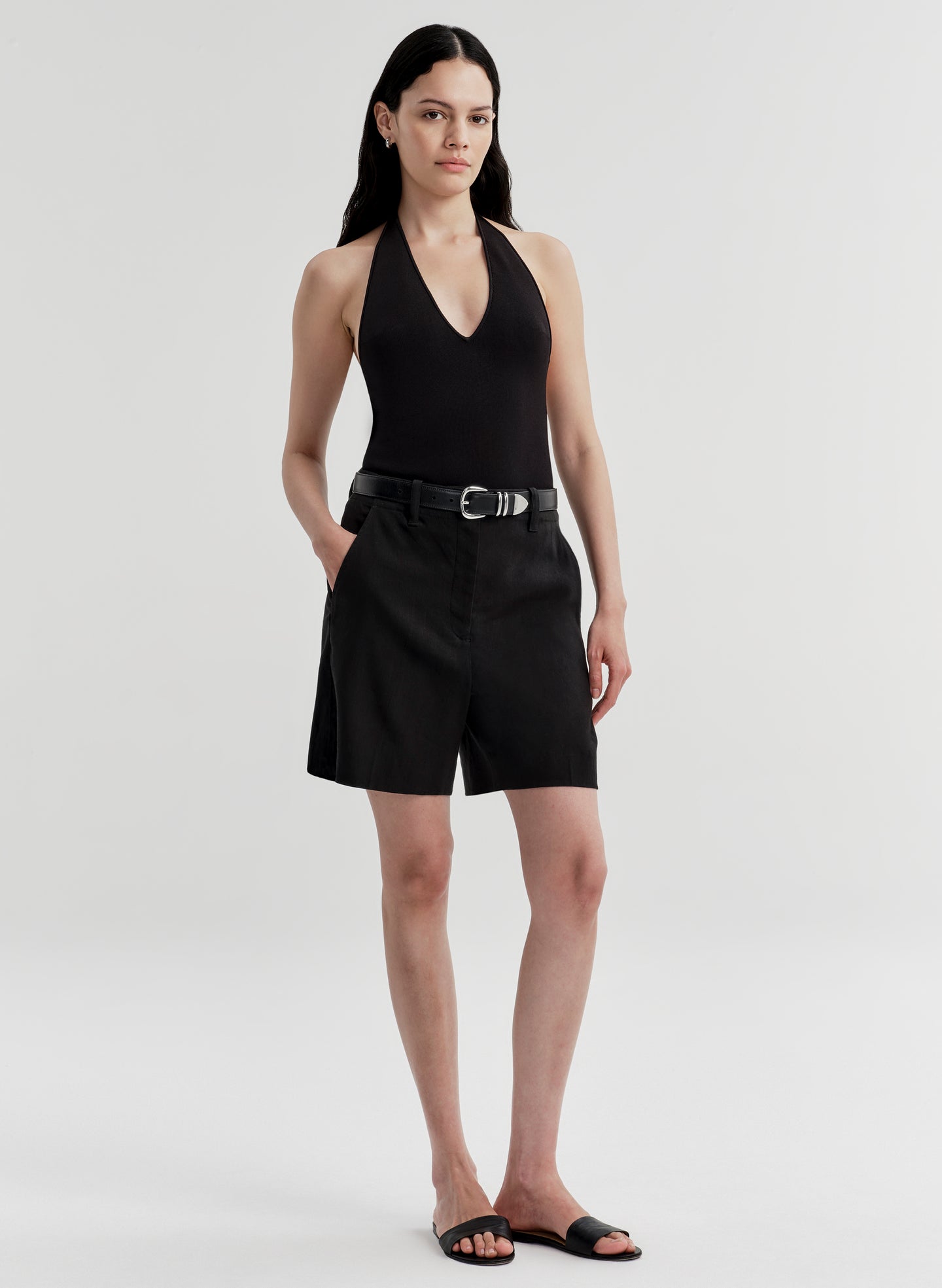 Woman wearing a black halter top and black shorts on a white background