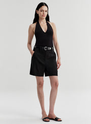 Woman wearing a black halter top and black shorts on a white background
