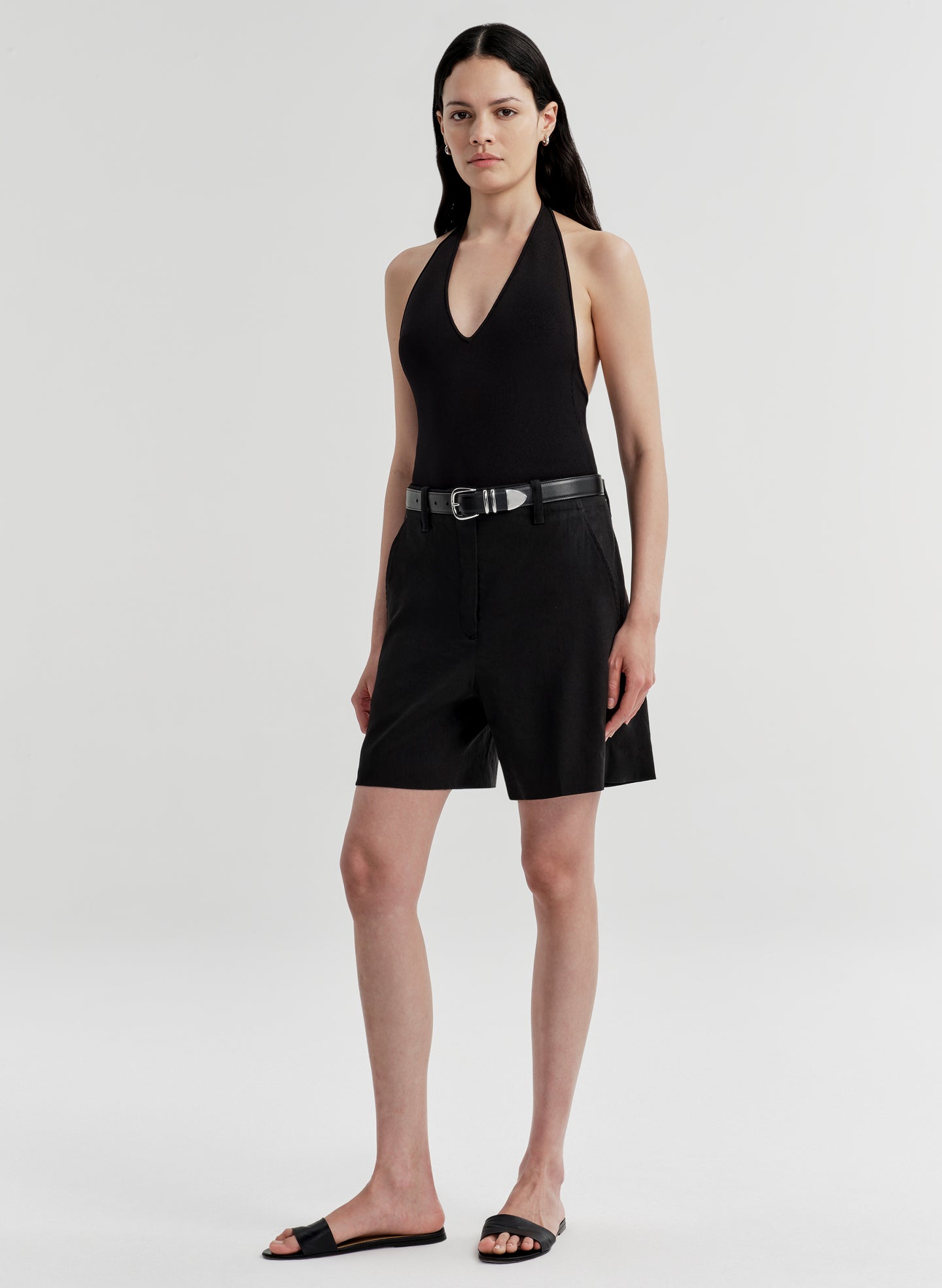 Woman wearing a black sleeveless top and shorts on a white background
