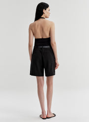 Woman wearing a black halter top and shorts on a white background