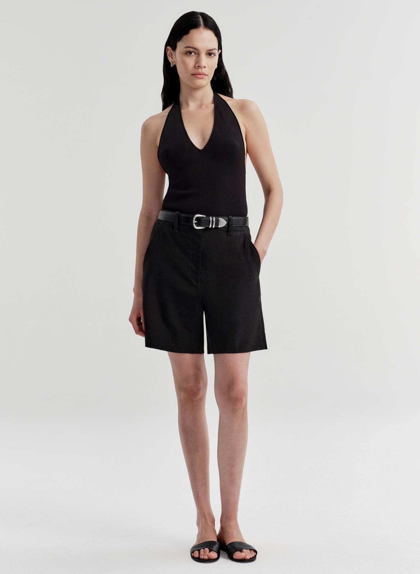 Woman wearing black linen shorts with a matching top on a white background