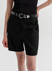Woman wearing black linen shorts with a matching top on a white background
