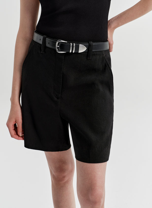 Woman wearing black linen shorts with a matching top on a white background