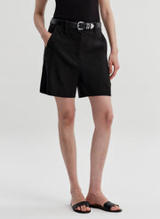 Woman wearing black linen shorts on a white background