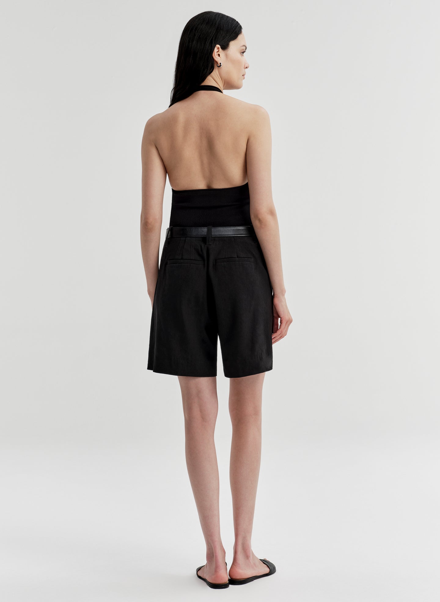 Woman wearing black linen shorts with a matching top on a white background