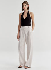 Woman wearing a black halter top and light colored pants on a light gray background