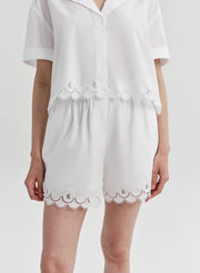 Woman wearing white lace-trimmed shorts on a white background