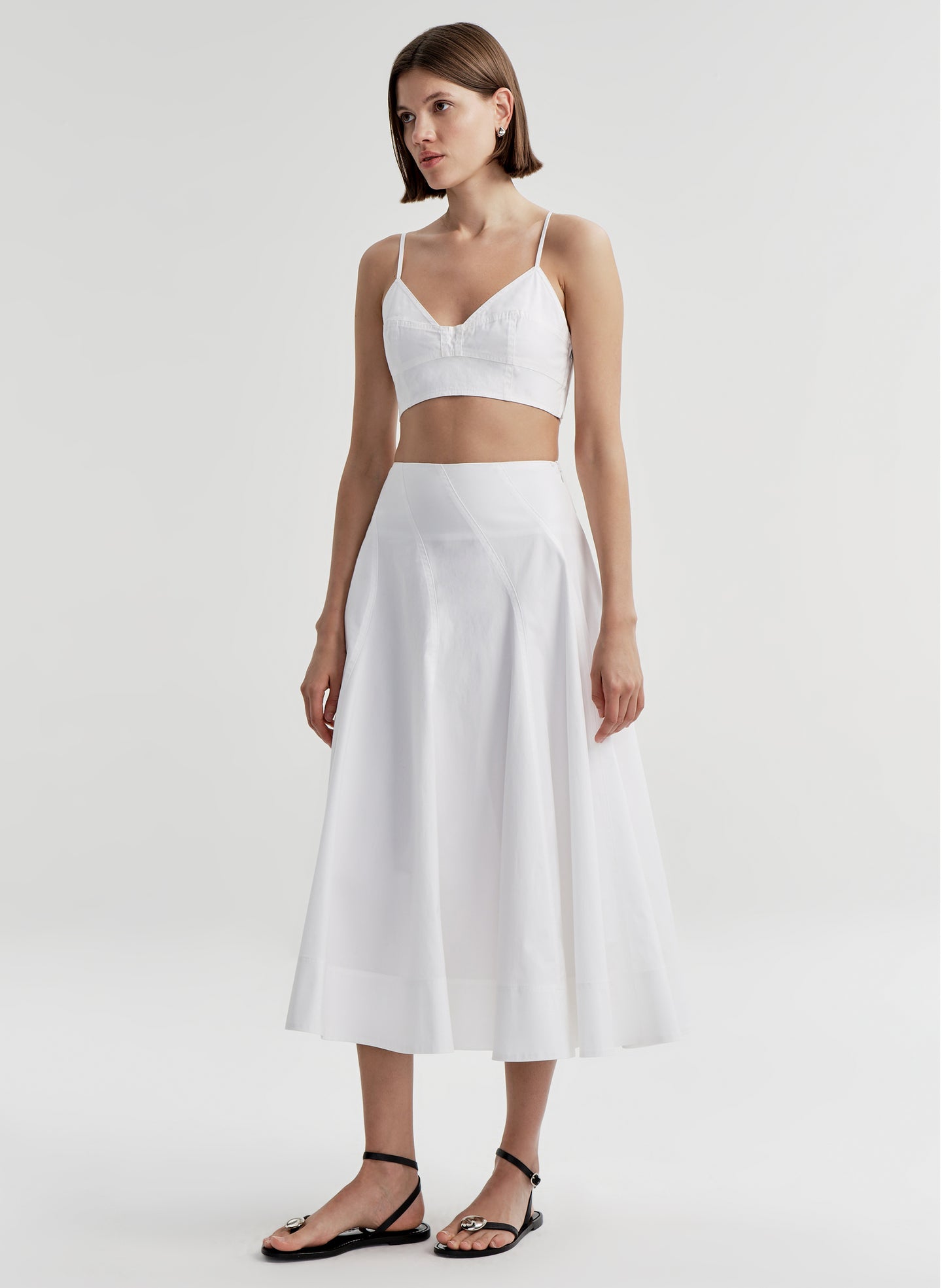 Woman wearing a white skirt and matching top on a plain background