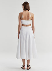 Woman wearing a white skirt and matching top on a plain background