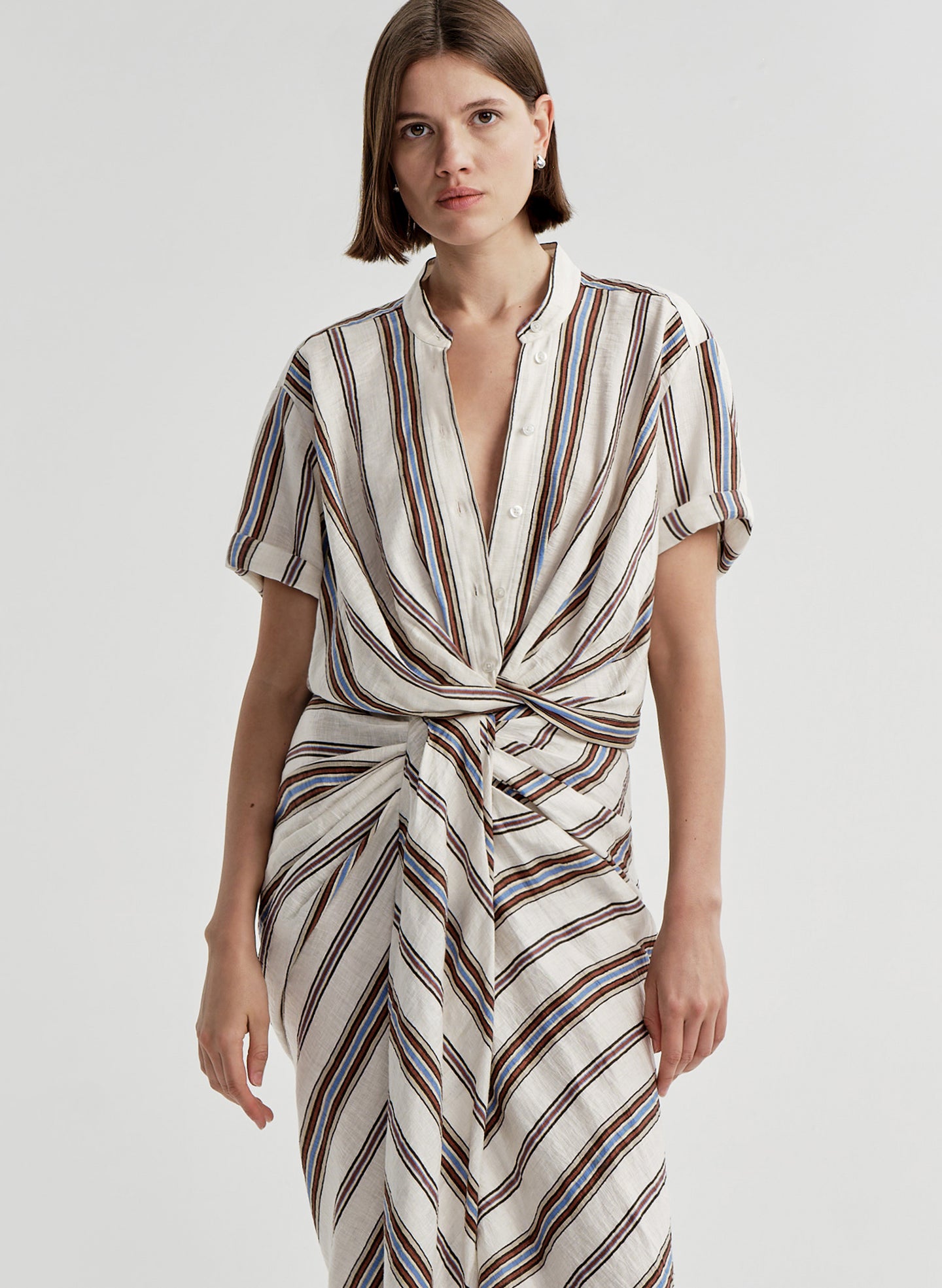 Woman wearing a striped linen top with a matching skirt and a plain background