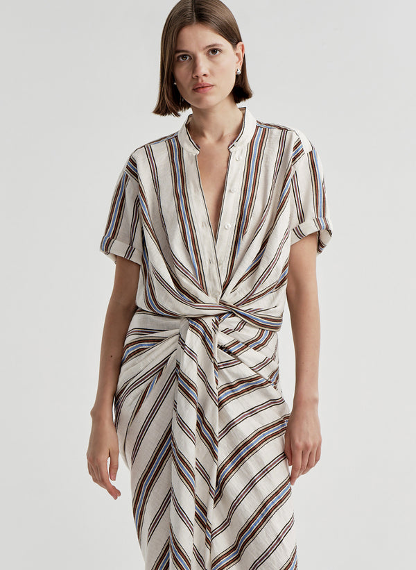 Woman wearing a striped linen top with a matching skirt and a plain background