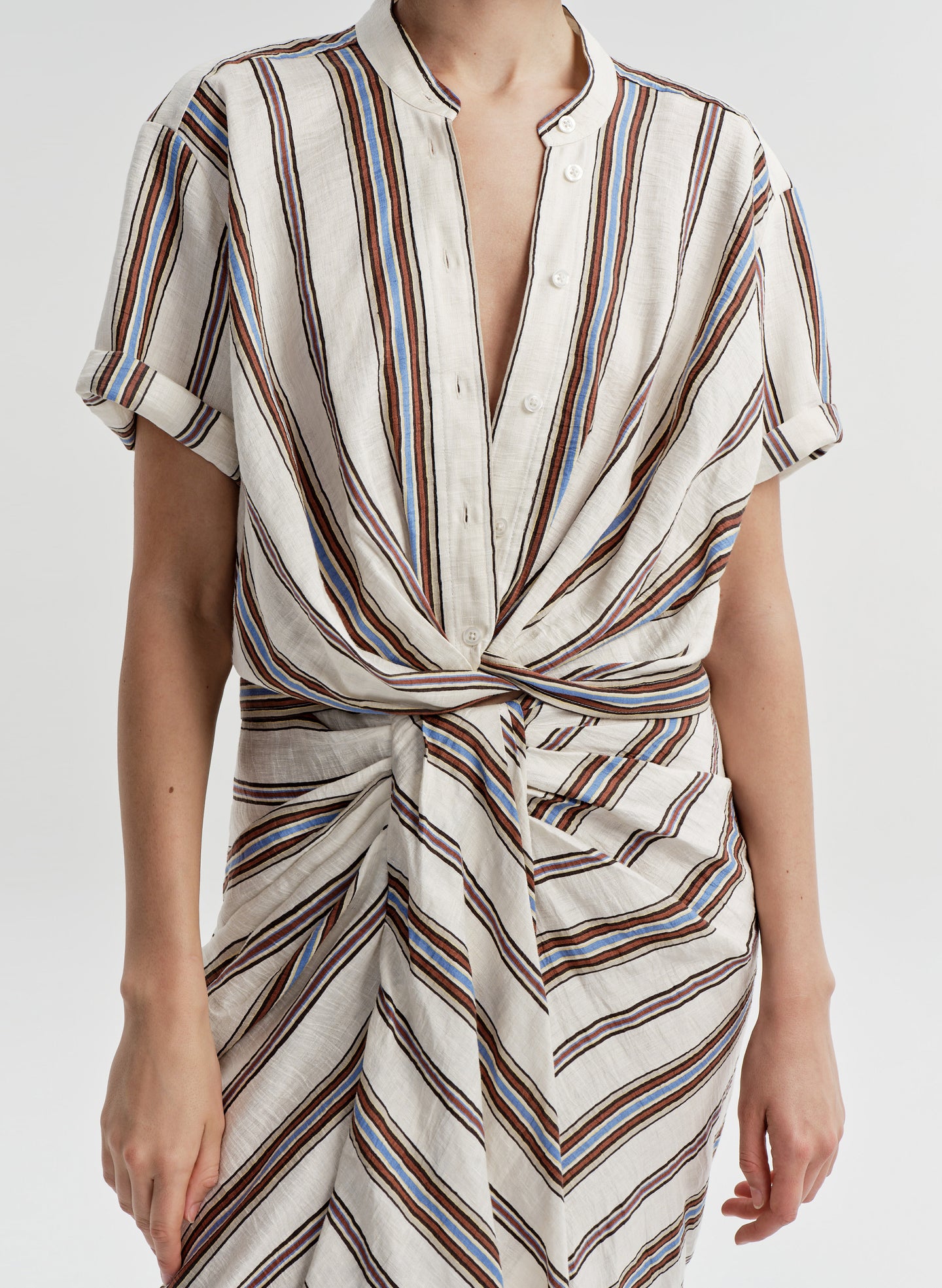 Woman wearing a striped linen top with a matching skirt and a plain background