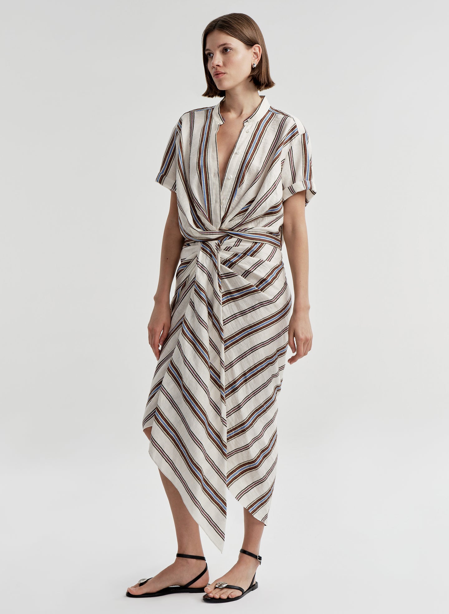 Woman wearing a striped linen top with a matching skirt and a plain background