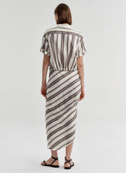 Woman wearing a striped linen skirt with a matching top on a plain background