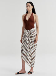 Woman wearing a brown halter top and striped skirt on a white background