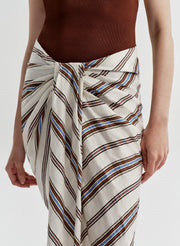 Person wearing a brown top and striped white, blue, and brown skirt on a white background