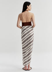 Woman wearing a brown halter top and striped sarong on a white background
