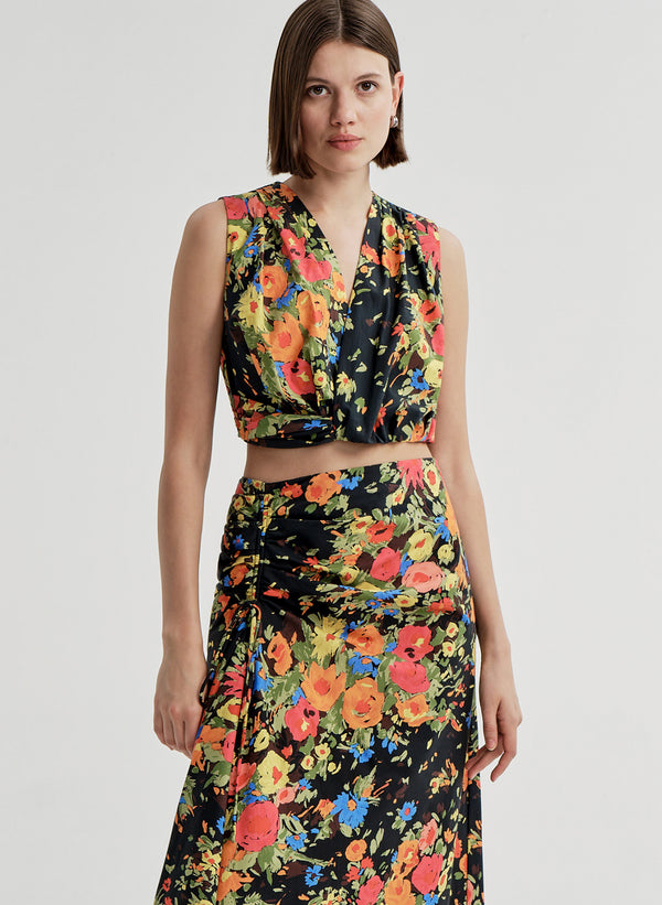 Woman wearing a sleeveless floral top with a matching skirt on a white background