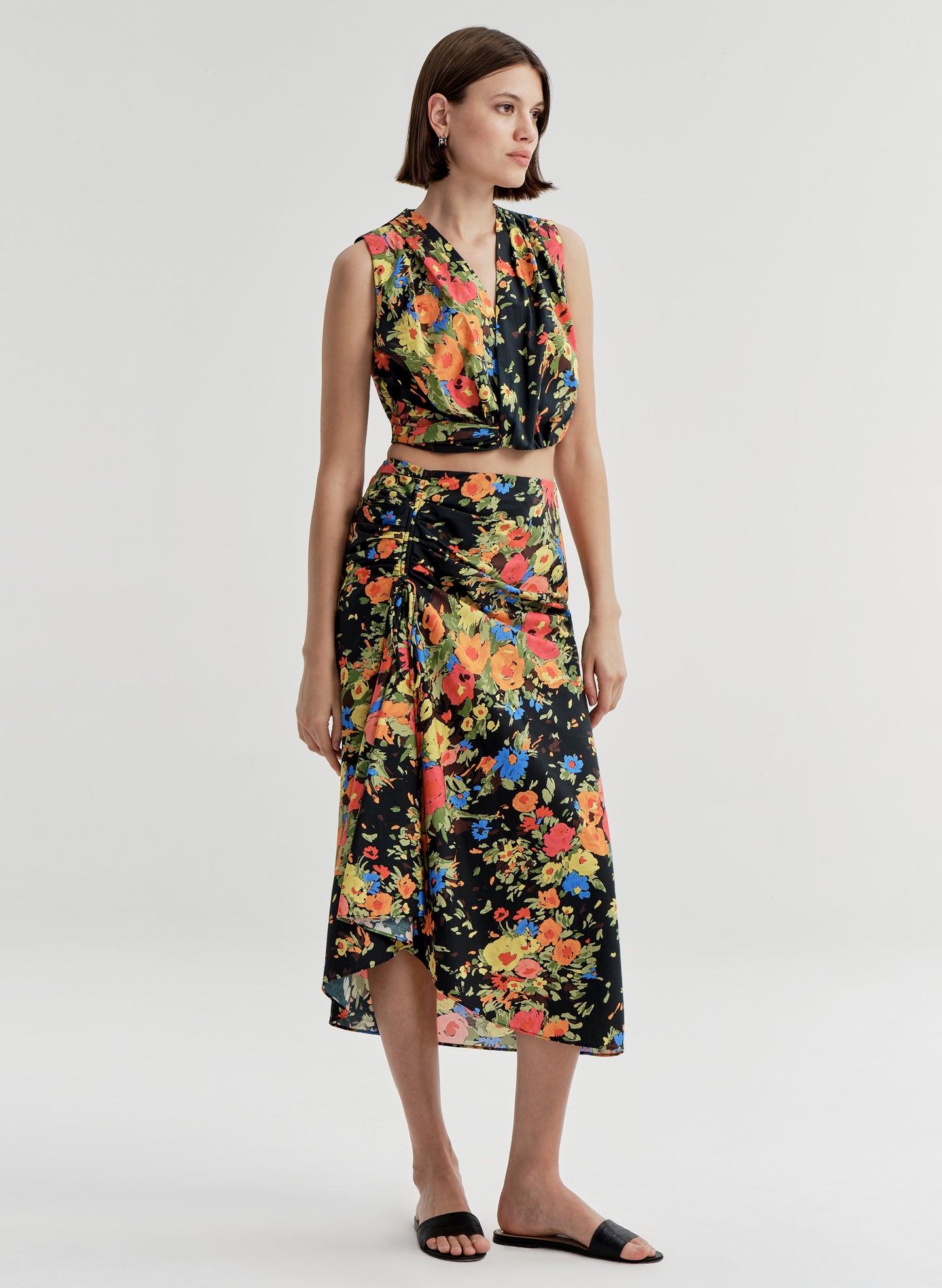 Woman wearing a sleeveless floral top with a matching skirt on a white background